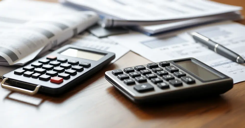 Documentos impressos, calculadora e caneta sobre a mesa