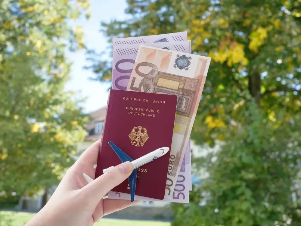 Mão segurando um passaporte com notas de euro dentro